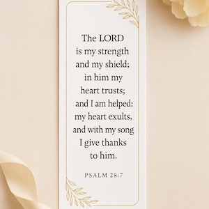 Op de afbeelding: Een rechthoekige witte kaart met gouden bloemaccenten en tekst uit Psalm 28:7. De tekst luidt: "De HEER is mijn kracht en mijn schild; op Hem vertrouwt mijn hart; en mij is geholpen: mijn hart jubelt, en met mijn lied dank ik Hem."