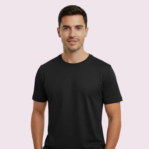 May include: A black crew neck t-shirt. The short-sleeved shirt is made of a soft material. The model is wearing the shirt. The background is a light pink color.