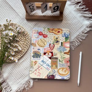 May include: A decorative tablet case featuring a collage of vintage-style illustrations. The design includes images of cherries, pastries, blueberries, a jar of strawberry jam, and a coffee cup. A wooden calendar displays "OCT 19".