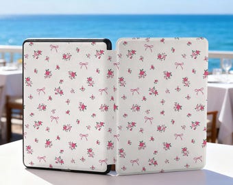 May include: A white e-reader cover with a floral pattern of pink roses and bows. The cover is open, revealing the device's screen. The background shows a bright blue ocean and sky.