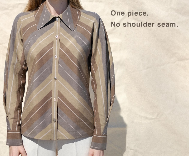 May include: A long-sleeve button-down shirt featuring a brown, tan, and grey chevron stripe pattern with a pointed collar and buttoned cuffs. The text on the image reads: One piece. No shoulder seam.