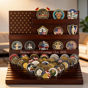 May include: A wooden display case with multiple shelves, showcasing a collection of commemorative coins. The display features an American flag design and the inscription "Honour • Duty • Courage • Est. 2026". The coins have various designs and colors.