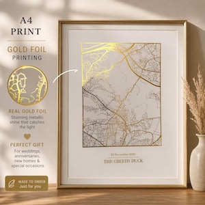 May include: A framed A4 print with a gold foil map design. The map shows roads and buildings, with the text "23 November 2024 THE GREEDY DUCK" at the bottom. The frame is gold, and the print is on a white background. The print is described as a perfect gift.