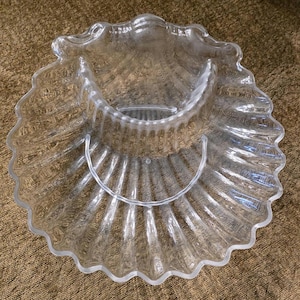 Puede incluir: Plato para servir transparente con borde festoneado con diseño de concha. El plato tiene un cuenco central para salsas y un asa. El plato de cristal transparente es ideal para servir aperitivos o snacks. El plato tiene unos 30 cm de diámetro.