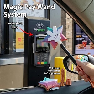 May include: A multi-colored star-shaped wand with a white hand design, used for contactless payment. The image shows the wand near a McDonald's payment terminal, with the text "Magic Pay Wand System" and "Insert Card Here". Additional 3D printed accessories are also visible.
