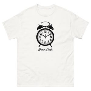 May include: White t-shirt featuring a black alarm clock graphic. The alarm clock design includes a clock face with numbers and hands, and the words "Alarm Clock" are printed below the clock.
