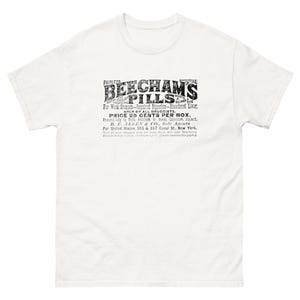 May include: White t-shirt featuring a vintage advertisement for "Beecham's Pills." The black text includes the product name, a list of ailments, and the price of 25 cents per box. The shirt has short sleeves and a crew neck.