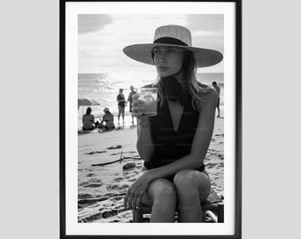 Kate Moss con cappello da sole beve acqua e limone, stampa fotografica in bianco e nero sulla spiaggia, decorazione murale minimalista, poster chic costiero