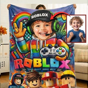 Puede incluir: Una manta vibrante con una ilustración de dibujos animados de un niño con un sombrero y auriculares de Roblox, sosteniendo un mando de juego. La manta tiene un diseño de arcoíris y el logotipo de Roblox se muestra de forma destacada. La manta es un artículo suave y acogedor.