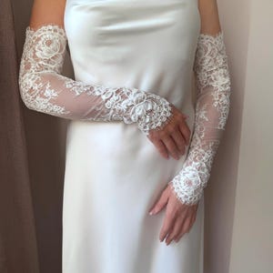 Bridal lace arm sleeves close up, sheer fingerless design with floral appliqué