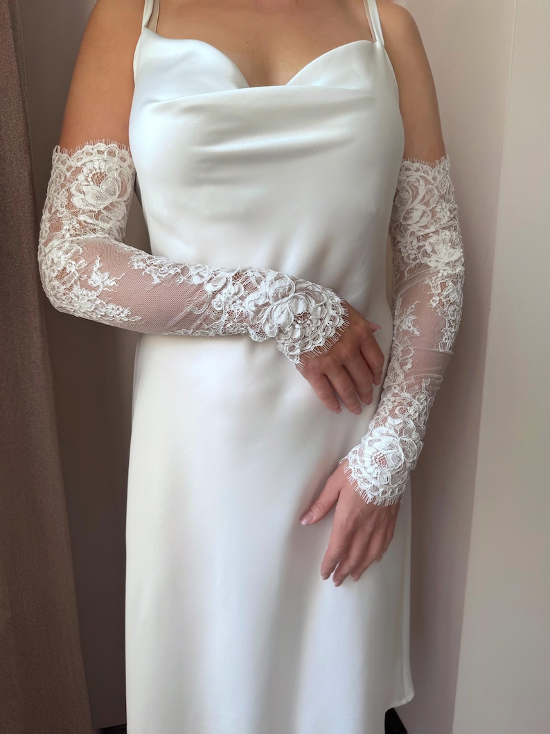 Bridal lace arm sleeves close up, sheer fingerless design with floral appliqué