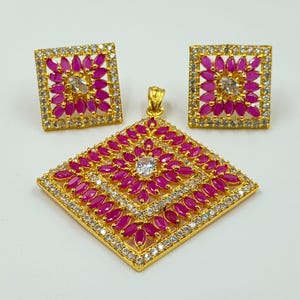 May include: A gold-tone jewelry set consisting of a square pendant and matching square stud earrings. Each piece features a central clear stone surrounded by marquise-cut fuchsia pink stones, all framed by a border of small clear white crystals.