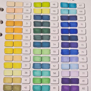 Pode incluir: Um gráfico de cores com amostras de cores numeradas, variando de amarelos e laranjas claros a azuis, roxos e rosas. O gráfico é organizado em linhas e colunas, com cada amostra rotulada com um número de 27 a 87.