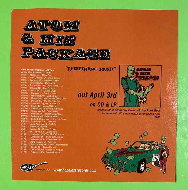 May include: Orange promotional flyer for Atom & His Package, featuring tour dates and album release information. The flyer includes a cartoon image of a green car and a band member. The text "Redefining Music" is displayed.