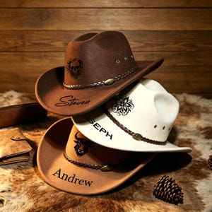 May include: Three cowboy hats stacked on top of each other. The top hat is brown with a skull design and the name "Steven". The middle hat is white with a floral design and the name "Joseph". The bottom hat is tan with a bull design and the name "Andrew".