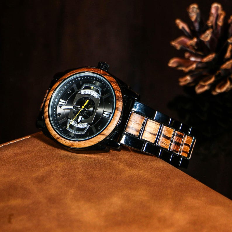 Puede incluir: Un reloj de pulsera negro con un bisel de madera y una esfera negra. El reloj tiene una correa de madera y metal negro. El reloj est&aacute; sobre una superficie de cuero marr&oacute;n.