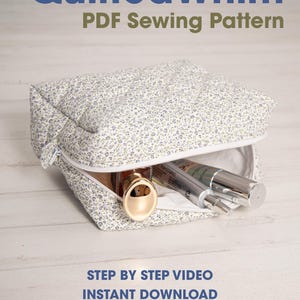 May include: A quilted cosmetic bag with a floral pattern, partially unzipped to reveal beauty products. The bag is white with a blue and green floral design. Text on the image reads "QuiltedWhim PDF Sewing Pattern".