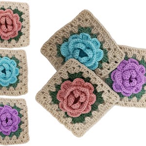 May include: Crocheted square coasters in various colors. Each coaster features a central flower design in pink, blue, or purple, surrounded by green and beige crochet. The coasters are handmade and suitable for home decor.
