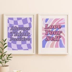 May include: Two framed art prints with positive affirmations. One features a purple checkered pattern with the text "Always Think Positive." The other has a wavy design in pink, blue, and purple, with the words "Love Your Self."