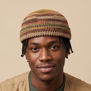 Puede incluir: Un gorro tejido a ganchillo con rayas horizontales en tonos marrón, verde y amarillo. El sombrero lo lleva una persona. El sombrero es un gorro redondo y ajustado, adecuado para ropa informal.