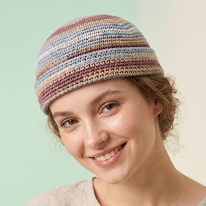 Könnte beinhalten: Eine runde, randlose Beanie-Mütze aus dichtem Häkelmuster. Die Mütze zeigt horizontale Streifen in gedeckten Tönen von Altrosa, Hellblau, Beige und Creme, mit einem dicken, umgeschlagenen Bündchen am unteren Rand der Kopfbedeckung.