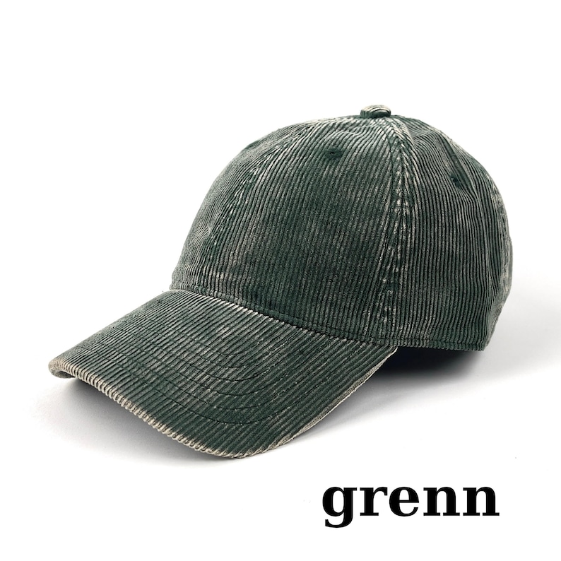 May include: A dark green corduroy baseball cap with a curved brim. The cap has a distressed, vintage look. The word "grenn" is printed in black at the bottom of the image. This hat is a stylish accessory.