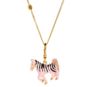 Puede incluir: Un collar dorado con un colgante de cebra rosa y negro. El colgante de cebra tiene pezu&ntilde;as doradas y una brida dorada. La cadena del collar tambi&eacute;n es dorada.