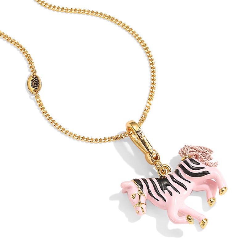 Puede incluir: Un collar dorado con un colgante de cebra rosa y negro. La cebra tiene un cuerpo rosa con rayas negras y una melena rosa. La cadena es una delicada cadena de eslabones.