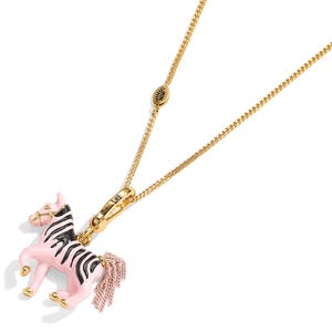 Puede incluir: Collar dorado con un colgante de cebra rosa y negro. El dije de cebra tiene un cuerpo rosa con rayas negras y una cola de borla rosa. El collar tiene una cadena delicada y un cierre de mosquet&oacute;n.