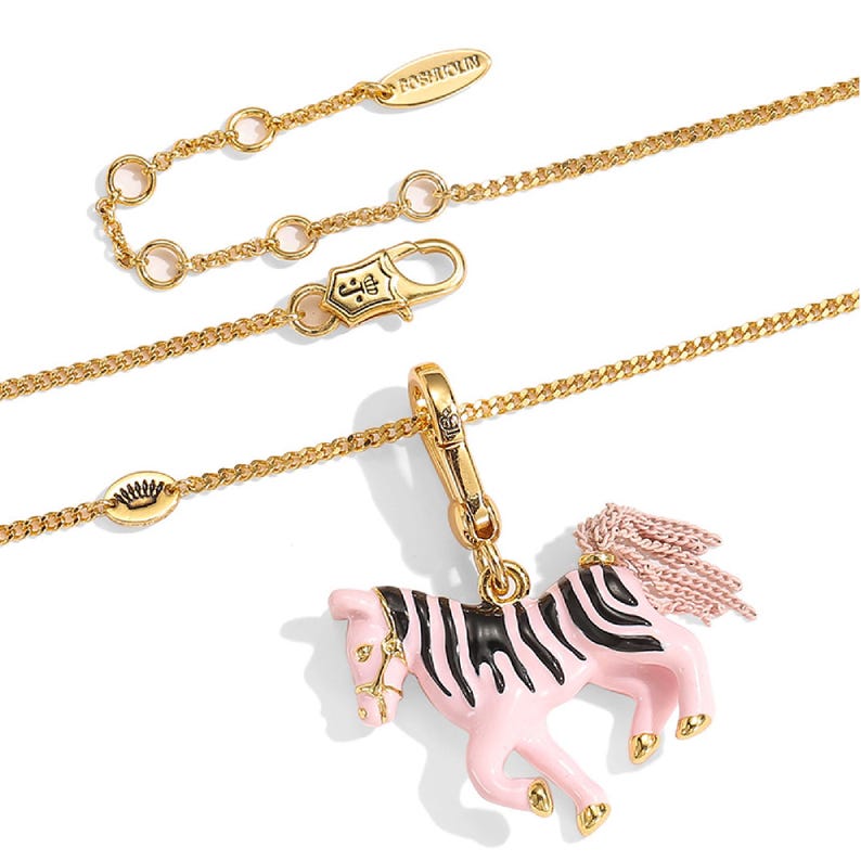 Puede incluir: Collar dorado con un colgante de cebra rosa y negro. El colgante tiene un cuerpo rosa con rayas negras y una melena de borlas rosas. El collar tiene un cierre de mosquet&oacute;n y una cadena ajustable.