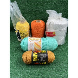 May include: Five spools of macrame and craft cord in yellow, orange, white, mint green, and mustard. The yellow and white cords are in clear plastic bags. Labels include Poly-O Cord, Wonder Twist 6mm, and Omni Macrame & Craft Cord 5mm.