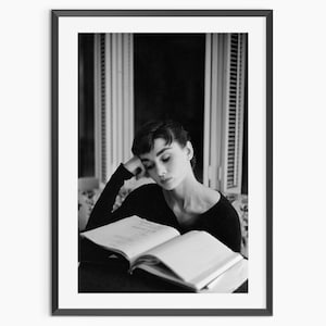 Può includere: Stampa incorniciata in bianco e nero raffigurante una persona che legge un libro. La persona è appoggiata sul braccio, guardando il libro aperto. Lo sfondo presenta una finestra.