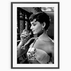 Könnte beinhalten: Schwarz-Weiß-Druck in einem Rahmen mit dem Porträt einer Frau, die ein Glas hält. Sie trägt ein trägerloses Kleid mit floralem Design und Perlenohrringe. Ein klassisches Hollywood-Porträt.