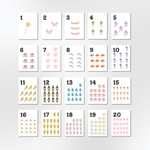 May include: A collection of 20 small, white cards, each featuring a different watercolor illustration. The illustrations include a star wand, butterflies, rainbows, fairies, mushrooms, teacups, and more. The cards are arranged in a grid.