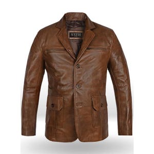 May include: A brown leather blazer with a classic design. Features include a notched lapel, two zippered chest pockets, two flap pockets, and a three-button closure. The label inside the jacket reads "SATH".