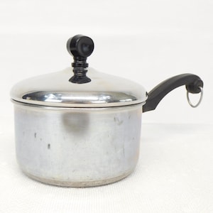 May include: A stainless steel saucepan with a lid and a black handle. The lid has a black knob. The handle has a metal ring. The pot is designed for cooking.