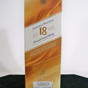 May include: A gold and white box for Johnnie Walker 18 year old blended Scotch whisky. The box features a gold label with the Johnnie Walker logo and the text "Aged 18 Years". The box also features a gold image of a man walking with a stick.