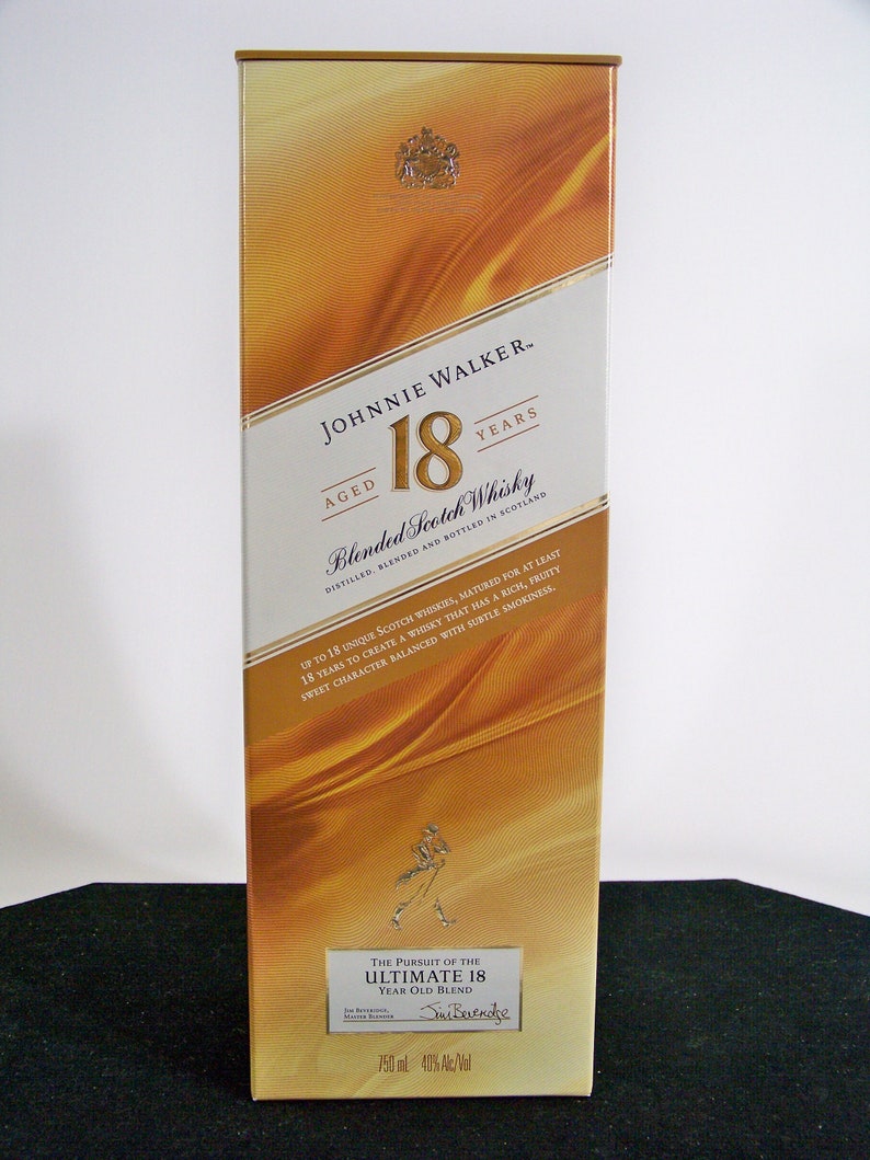 May include: A gold and white box for Johnnie Walker 18 year old blended Scotch whisky. The box features a gold label with the Johnnie Walker logo and the text "Aged 18 Years". The box also features a gold image of a man walking with a stick.