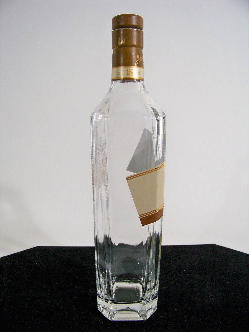 May include: A clear glass bottle with a brown cap and a label that says "Johnnie Walker 18 Years Old".