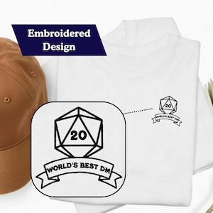 May include: White t-shirt with an embroidered design featuring a black D20 die and the text "World's Best DM". A brown baseball cap is visible on the left. The shirt is folded.