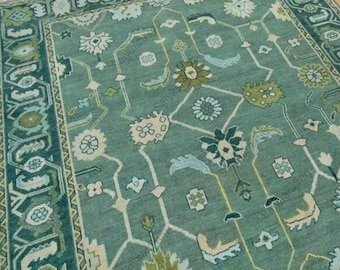 May include: A teal-colored area rug with a floral pattern. The rug features a central design of stylized flowers and geometric shapes in shades of green, cream, and blue. The border is a darker teal with repeating patterns.