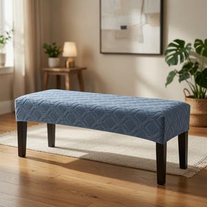 Può includere: Una panca rettangolare con un rivestimento in tessuto blu caratterizzato da un motivo geometrico a rombi in rilievo. La panca è sostenuta da quattro gambe dritte in legno marrone scuro che offrono una base stabile per la seduta.