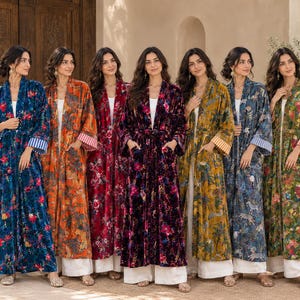 Peut inclure: Une collection de sept peignoirs en velours à manches longues dans des couleurs variées, notamment bleu, orange, rouge, violet, jaune et vert. Chaque peignoir présente un motif floral et animalier, une ceinture et des poignets rayés.
