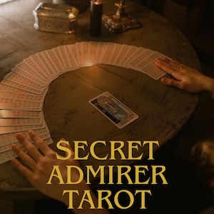 Pode incluir: Uma configuração de leitura de tarot com um baralho de cartas em leque sobre uma mesa de madeira. Um único cartão é exibido, e o texto "SECRET ADMIRER TAROT" é visível, junto com "same day". Uma vela acesa e outros itens decorativos também estão presentes.