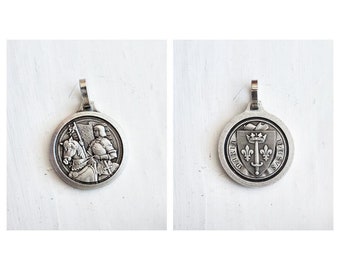 May include: Silver pendant featuring a knight on horseback on one side and a coat of arms with a sword and fleur-de-lis on the other side. The coat of arms has the text "D.G. REX.S." around it.