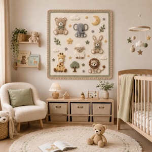 May include: A nursery scene featuring a beige and cream color scheme. A large, square, cream-colored blanket with crocheted animal figures hangs on the wall. A wooden crib, chair, and storage unit complete the room. A mobile with stars and clouds hangs above the crib.