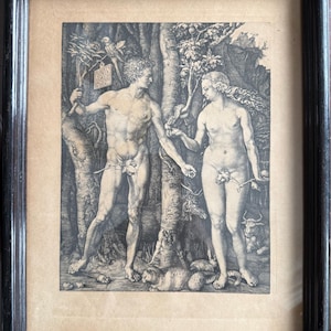 Könnte beinhalten: Gerahmter Schwarz-Weiß-Druck von Adam und Eva in einem Wald. Das Kunstwerk zeigt einen nackten Mann und eine nackte Frau, eine Schlange und verschiedene Tiere. Der Druck befindet sich in einem dunklen Holzrahmen.