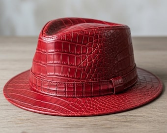 May include: A red fedora hat with a textured, crocodile-like pattern. The hat has a wide brim and a band around the crown. The hat is made of a leather-like material.