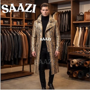 May include: A long trench coat featuring a tan and black snakeskin pattern, a wide collar, and two front flap pockets. The coat is worn over a black turtleneck sweater and black trousers. The text SAAZI is visible on the coat and background.