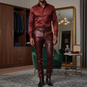 May include: A burgundy satin dress shirt paired with burgundy snake-print leather pants and black boots. The outfit is worn in a room with a green chair, a gold-framed mirror, and a wooden wardrobe.